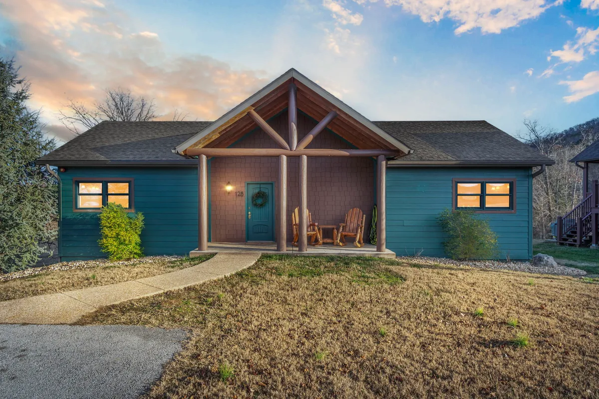 A welcoming front porch adorned with classic rocking chairs, surrounded by lush greenery and a charming entrance door. The atmosphere is cozy and tranquil, suggesting peaceful mornings or evenings spent enjoying each other's company and the views.