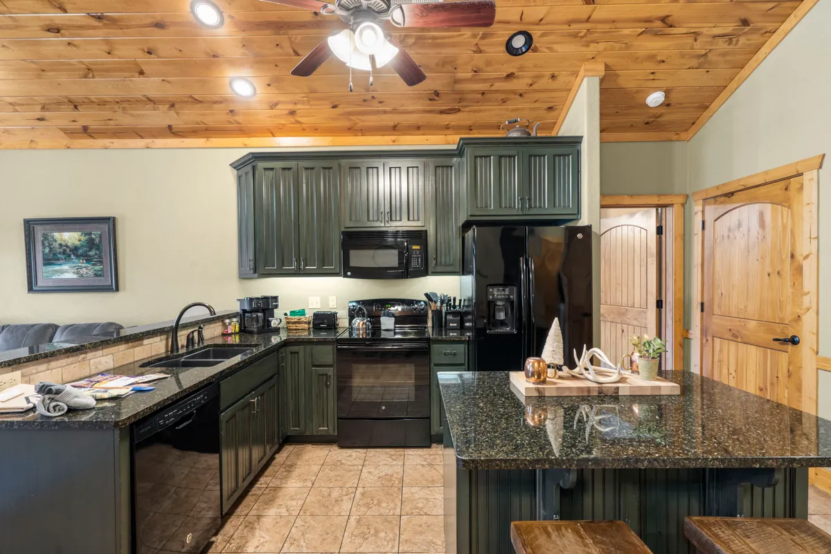 A welcoming kitchen space featuring a granite countertop, black modern appliances, and warm wooden cabinets. The area is cozy and functional, perfect for cooking family meals or preparing the day's fresh catch. The setup encourages group cooking and gathering.